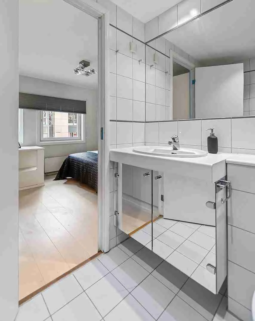 Matching Hardwood Floors with Vinyl, Tile, or Carpet 2 Bathroom with tiled flooring next to a bedroom with light wood floors, showing functional flooring choices