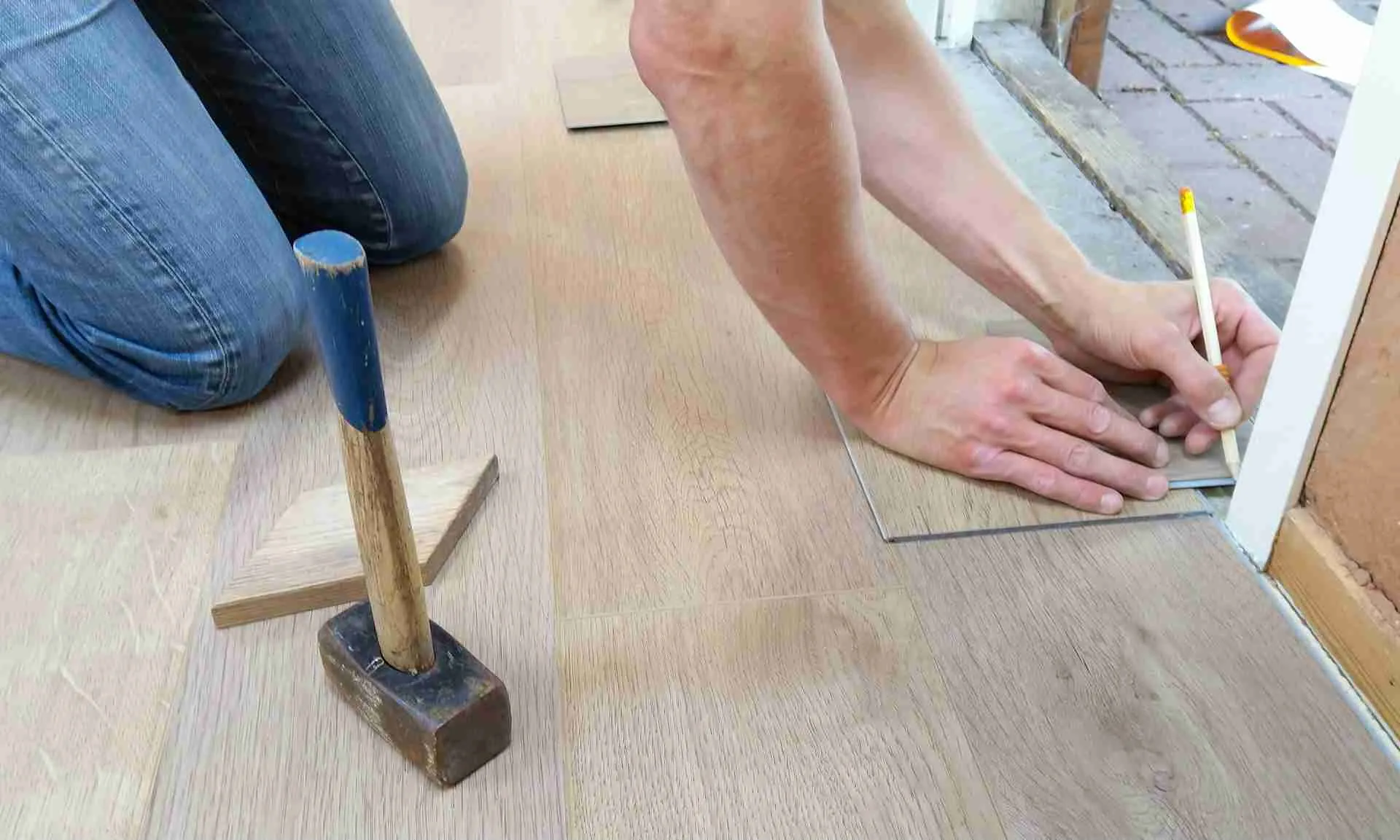 Stylish Flooring Ideas to Boost Your Home’s Resale Value 1 Worker measuring and installing laminate flooring with tools on hardwood surface